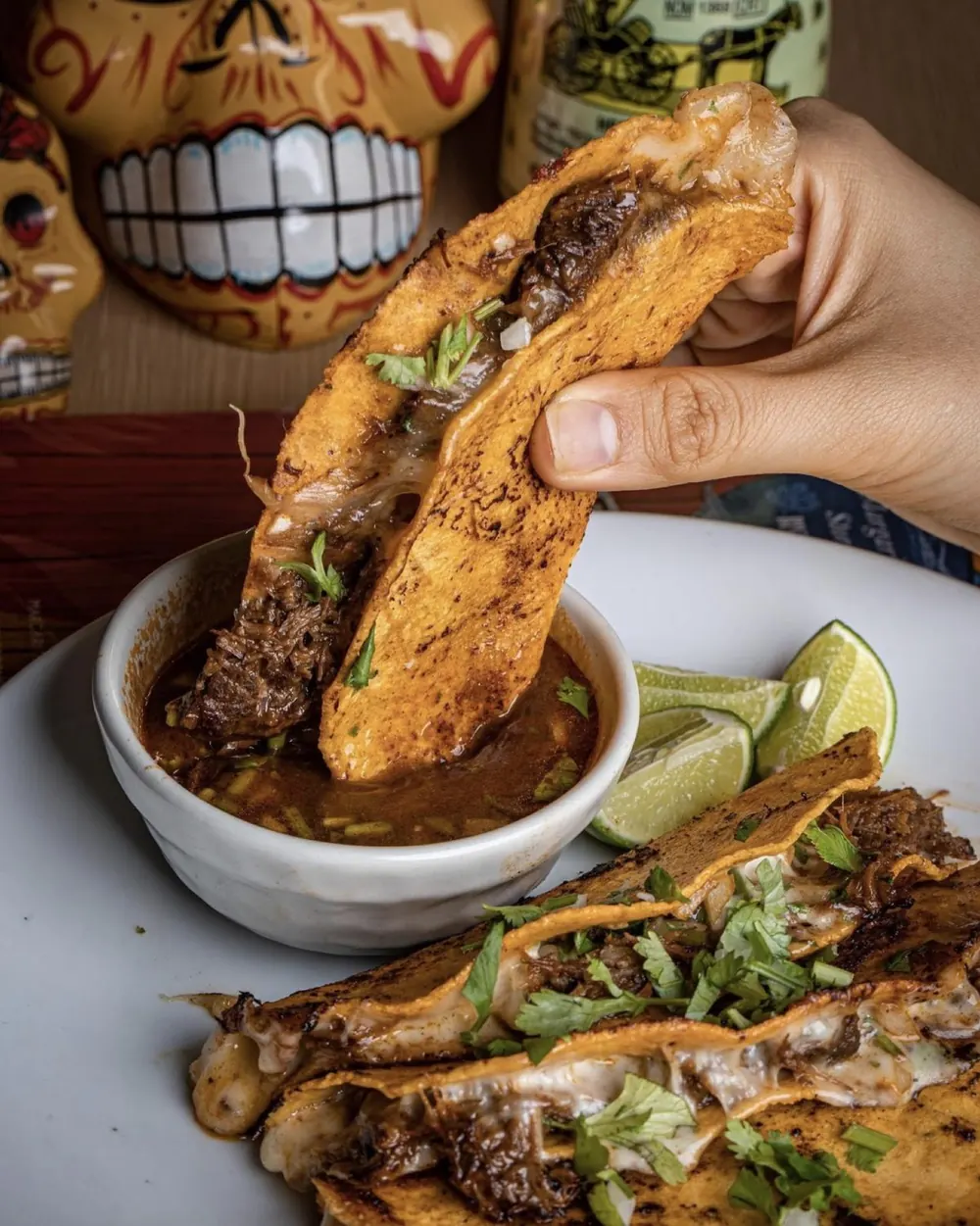 Quesa birria taco dipped into consomé
