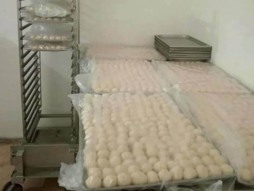 Trays of flour tortilla dough balls next to a rolling tray rack in the kitchen